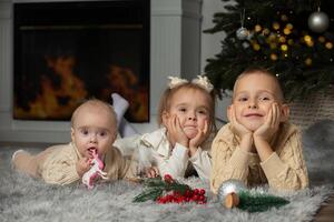 Overjoyed small children in santa hats have fun unpack wrapped presents on merry Christmas morning near fir tree. photo