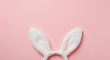 Easter Bunny Ears on Soft pink Pastel Background. A top-down view of cute rabbit ears in a simple yet elegant Easter-themed composition, ideal for digital designs and seasonal decorations photo
