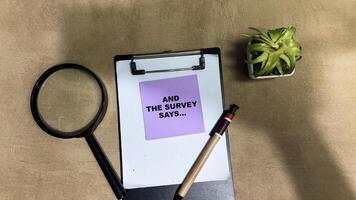 Concept of And The Survey Says write on sticky notes isolated on Wooden Table. photo
