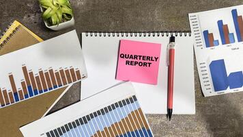 Concept of Quarterly Report write on sticky notes isolated on Wooden Table. photo