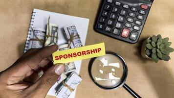 Concept of Sponsorship write on sticky notes isolated on Wooden Table. photo