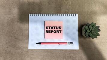 Concept of Status Report write on sticky notes isolated on Wooden Table photo