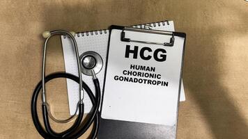 Concept of HCG - Human Chorionic Gonadotropin write on paperwork isolated on Wooden Table. photo