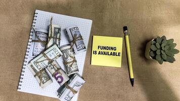 Concept of Funding is Available write on sticky notes isolated on Wooden Table. photo
