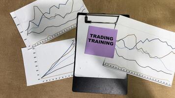 Concept of Trading Training write on sticky notes isolated on Wooden Table. photo