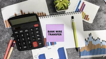 Concept of Bank Wire Transfer write on sticky notes isolated on Wooden Table. photo