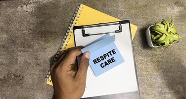 Concept of Respite Care write on sticky notes isolated on Wooden Table. photo