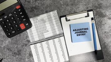 Concept of Adjusting Journal Entry write on sticky notes isolated on Wooden Table. photo