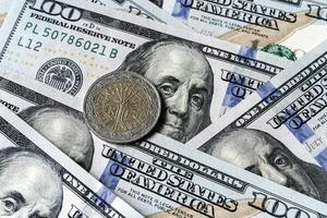A close up of a one dollar coin on top of a stack of us dollars photo