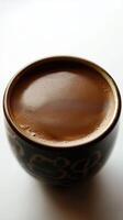 A floral-patterned mug of frothy coffee with rich brown foam viewed from above on a white background photo