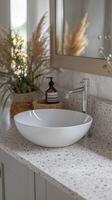 Terrazzo countertop with white round ceramic sink, minimalist modern bathroom featuring neutral tones photo