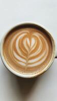 A cup of hot cappuccino with intricate latte art in a heart shape against a white background photo