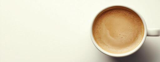 Top view of a cup filled with frothy cappuccino on a white background, copy space photo