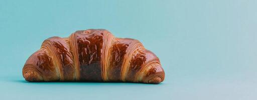Delicious croissant with crisp layers and golden finish against a pastel blue background, copy space photo