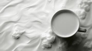 Cup of milk surrounded by cloud-like patterns on a creamy white background in black and white tones photo