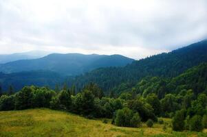 Lush forested mountains under a cloudy sky with rolling hills and vast greenery photo
