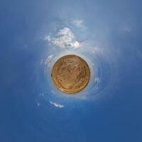 A small planet with a blue sky and clouds photo
