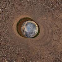 A circular hole in the ground with a sky in the middle photo