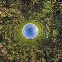 A circular view of a grassy field with a sky in the middle photo