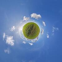A small planet with a grassy field and clouds photo