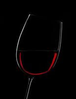Elegant red wine glass illuminated against a dramatic black backdrop photo
