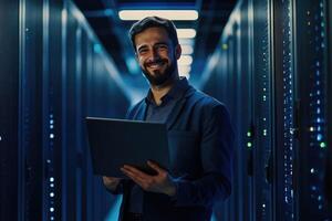 A man in a server room holding a laptop photo
