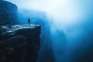 Man standing on edge of cliff in foggy mountain photo