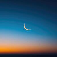 The crescent moon is seen in the sky at sunset photo