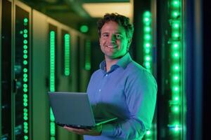 A man standing in a server room holding a laptop photo
