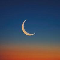 The crescent moon is seen in the sky at sunset photo