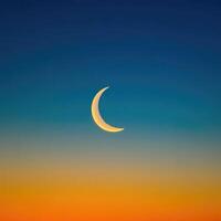 The crescent moon is seen in the sky at sunset photo