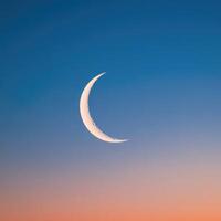 The crescent moon is seen in the sky at sunset photo