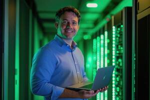 A man standing in a server room holding a laptop photo