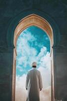 A muslim man standing in front of an archway photo