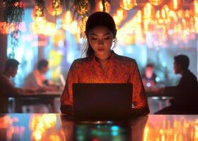 A woman is sitting at a table with a laptop photo