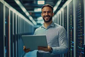 Smiling man holding laptop in data center photo