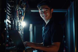 A man in black shirt smiling while using a laptop photo