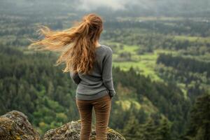 A woman standing on a rock overlooking a valley photo