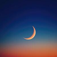 The crescent moon is seen in the sky at sunset photo