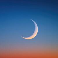 The crescent moon is seen in the sky at sunset photo