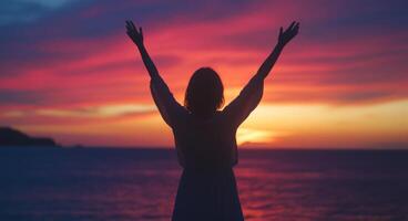 Woman with arms up in front of the sunset photo