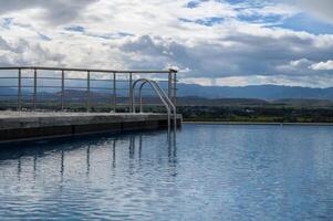 Serene infinity pool overlooking lush valleys and majestic mountains under a cloudy sky photo