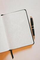 An open notebook with grid paper lies on a surface, accompanied by a pen placed neatly beside it photo