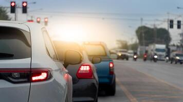 Line of cars stopped at a traffic light during daylight. Cars are in focus with a blurred background of more vehicles and traffic lights suggesting a busy intersection. photo