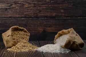 Raw and Processed Rice in Burlap Bags on Rustic Wooden Background photo