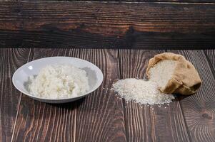 Fresh White Rice Poured from Bag on Wooden Table Surface photo