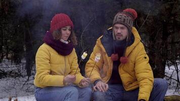 Young man and woman on a picnic in the winter forest. Tourists travel together. The guys are smiling and chatting. Travel and adventure concept. close-up video