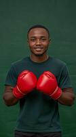 African American man wearing red boxing gloves smiles in studio setting with green background photo