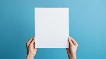A Hand Holding a Blank White Paper Against a Blue Background photo