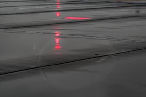 Jet nose reflected in rain-soaked runway with monochrome tones and red navigation light photo
